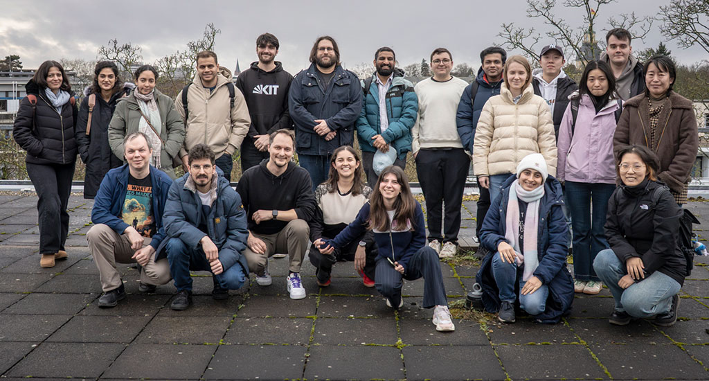 Group of people posing for a photo on a rooftop or open terrace, casual attire.